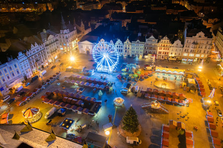 An aerial night shot of the Christmas markets in the square in Pilsen, featuring vibrant stalls surrounding the plaza and a large Ferris wheel lighting up the festive sceneの写真素材