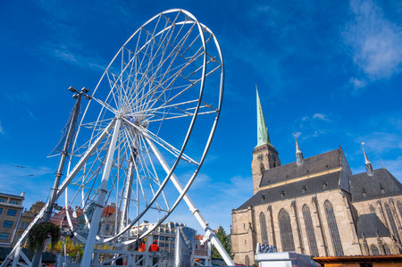 A stunning view of the Ferris wheel in the square in front of St. Bartholomew's Cathedral in Pilsen, adorned with festive lights during the Christmas markets.の写真素材