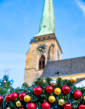 A festive scene with Christmas decorations in the foreground and the Cathedral of St. Bartholomew in Plzen, Czech Republic, in the background. A charming mix of tradition and holiday spiritの写真素材
