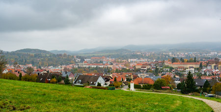 A panoramic view of Cesky Krumlov on an overcast autumn day, showcasing the town's historic rooftops, winding Vltava River, and iconic castle tower under a dramatic cloudy skyの写真素材
