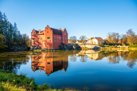 Panoramic view of Cervena Lhota Castle in the Czech Republic, surrounded by a lake reflecting its image. Autumn trees in vibrant colors and sunny weather create a picturesque, serene scene.の写真素材