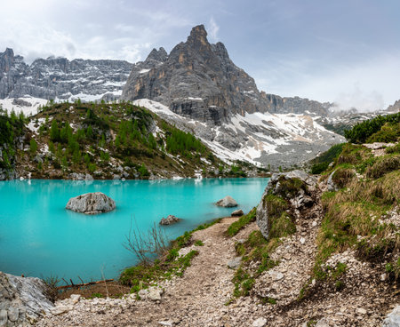 Panoramic view of Lago Sorapis in the Dolomites (Dolomiti, Dolomiten), Italy. The turquoise lake is surrounded by towering cliffs and mountains, a popular spot for hikers and nature loversの写真素材