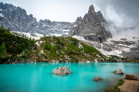 Panoramic view of Lago Sorapis in the Dolomites (Dolomiti, Dolomiten), Italy. The turquoise lake is surrounded by towering cliffs and mountains, a popular spot for hikers and nature loversの写真素材