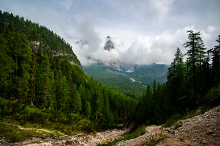 Mountain trail in the Dolomites (Dolomiti, Dolomiten), Italy, leading to Lago Sorapis. The path winds along rocky slopes with stunning views of valleys, forests, and peaksの写真素材