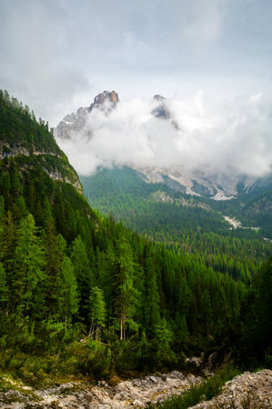 Mountain trail in the Dolomites (Dolomiti, Dolomiten), Italy, leading to Lago Sorapis. The path winds along rocky slopes with stunning views of valleys, forests, and peaksの写真素材