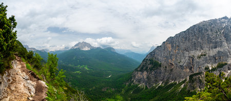 Breathtaking view of forests, mountains, and valleys in the Italian Dolomites (Dolomiti, Dolomiten). Captured from a scenic trail along a rocky ledge. Stunning alpine natureの写真素材