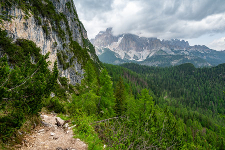 Breathtaking view of forests, mountains, and valleys in the Italian Dolomites (Dolomiti, Dolomiten). Captured from a scenic trail along a rocky ledge. Stunning alpine natureの写真素材