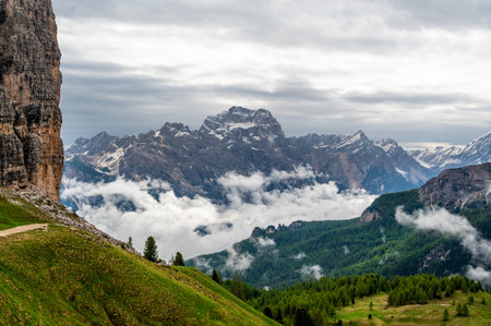 Mountain peaks around Cinque Torri in the Dolomites (Dolomiti, Dolomiten), Italy. Majestic summits partially covered in mist and clouds, with lush forests in the valleys belowの写真素材