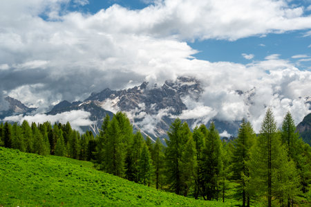 Mountain peaks around Cinque Torri in the Dolomites (Dolomiti, Dolomiten), Italy. Majestic summits partially covered in mist and clouds, with lush forests in the valleys belowの写真素材