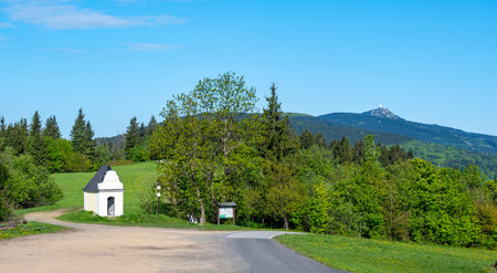 Panoramic view of Jested mountain with its iconic tower on the top, surrounded by green meadows, scattered cottages and small villages in the Czech countrysideの写真素材