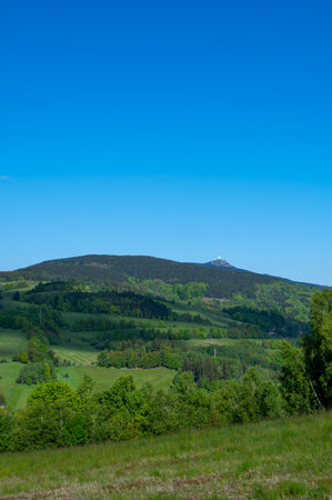 Panoramic view of Jested mountain with its iconic tower on the top, surrounded by green meadows, scattered cottages and small villages in the Czech countrysideの写真素材