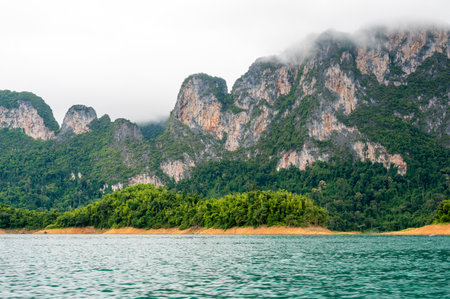 View of Khao Sok Lake in Krabi province, Thailand, with towering limestone cliffs covered in...