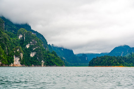 View of Khao Sok Lake in Krabi province, Thailand, with towering limestone cliffs covered in...