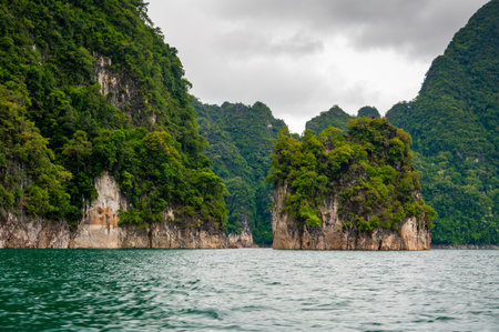 View of Khao Sok Lake in Krabi province, Thailand, with towering limestone cliffs covered in...