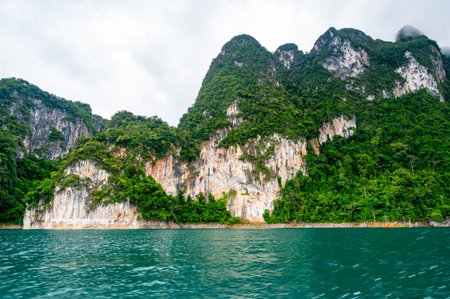 View of Khao Sok Lake in Krabi province, Thailand, with towering limestone cliffs covered in...