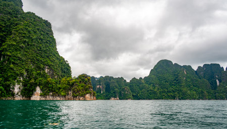 View of Khao Sok Lake in Krabi province, Thailand, with towering limestone cliffs covered in...