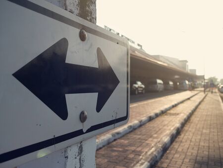 a road sign, with two black arrow, two directions onthe roadの写真素材