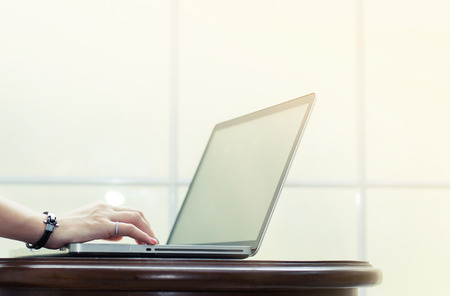 Hand is typing on  laptop on wooden table on white windowsill background.の写真素材