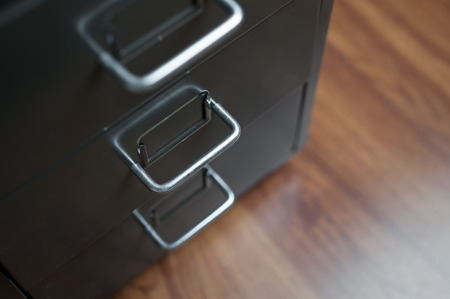 Close up of grey drawer with stainless handle on wooden floor.