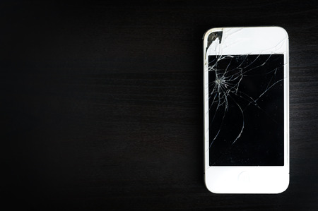Screen of mobile smartphone broken, Smartphone on dark wooden table background.の写真素材