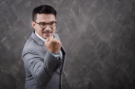 Successful businessman with arm up on grey background.の写真素材