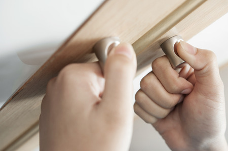 Closeup Hands of woman is holding on door handles of cabinet, Door handles of closet or wardrobe.の写真素材