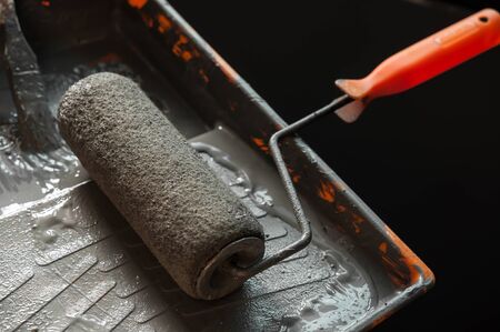 Close up of paint roller in paint tray, Grey paint in paint tray, Copy space, overhead view.の写真素材