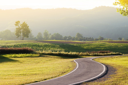 Road for bicycle or workout with grass field with mountains hill background in a fog.