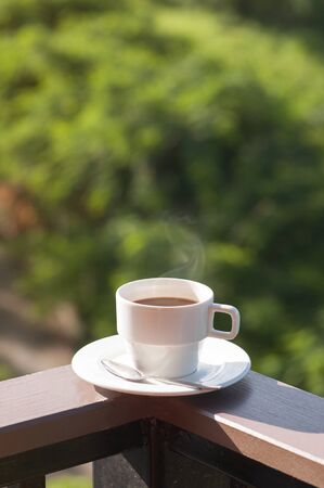 White cup of hot coffee on balcony with natural background. copy space.の写真素材