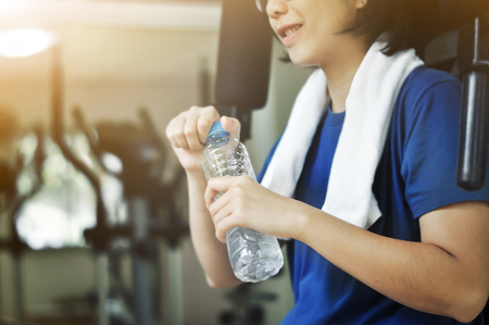 Asian woman holding bottle of water for drink after  workout in the gym.の写真素材