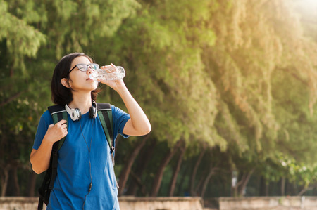 Asian woman traveller drinking water on nature background. copy space.の写真素材