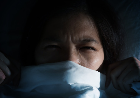 Nightmare concept. Dark tone. Asian women having trouble about getting up early in the morning. Girl hate sound from alarm clocks.の写真素材