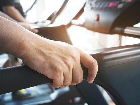 Close up man hands holding on treadmill machine while working out at a gym.の写真素材