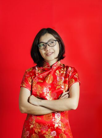 Chinese new year. Asian glasses woman with cheongsam on red background. Girl is smiling.の写真素材