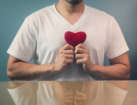 Valentine's day concept. Asian man holding red heart on blue background. Vintage and retro color.の写真素材