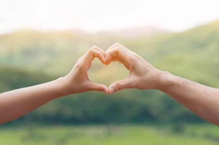 Woman hands in shape of love heart on natural background. Valentine's concept.の写真素材