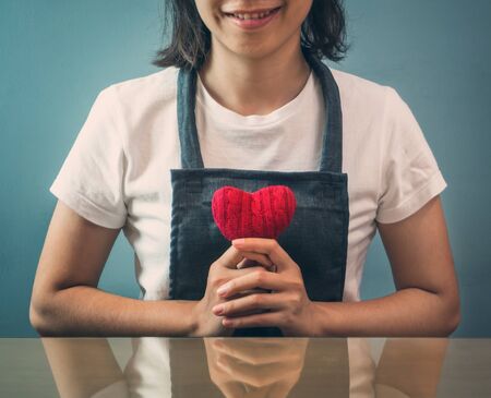 Valentine's day concept. Asian woman holding red heart on blue background. Girl is smiling. Vintage and retro color.の写真素材