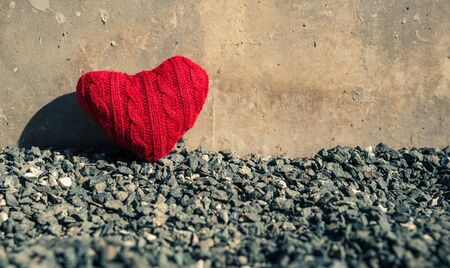 Valentine's concept. Red heart on dark grey gravel texture  background with copy space. Vintage and retro color.の写真素材