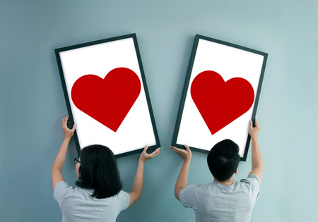 Separated Asian couple concept. Asian couple holding heart in picture frames. Rear view of lover.の写真素材