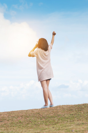 Asian woman holding balloon in shape of love heart with arms stretched on sky background. Freedom, Success, Valentine's day concept. Girl standing on peak of mountain.の写真素材