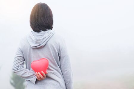 Woman holding red heart on fog background. Copy space.の写真素材