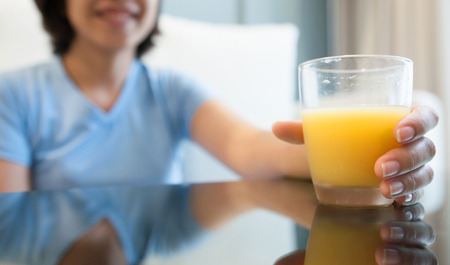 Woman hand holding glass of juice for drink. Orange juice.の写真素材