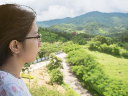 Asian woman standing at balcony and looking on the landscape.の写真素材