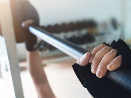 Close up man hands wear gloves with barbell at the gym.の写真素材