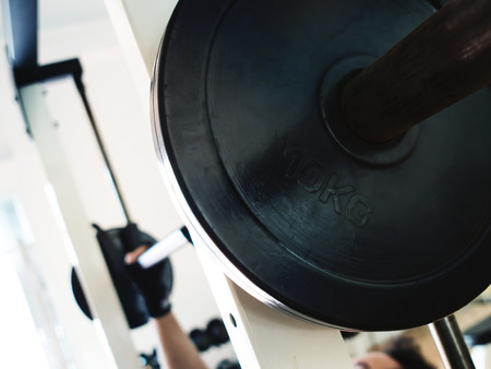 Close up man hands wear gloves with barbell at the gym.の写真素材
