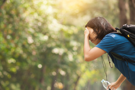 Close up Asian woman hiker pouring water from bottle on her face with nature background. copy space. Traveler.の写真素材