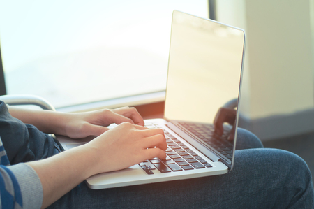 Woman hands using laptop for working and listening music with headphone when she travel. Blank screen laptop.の写真素材