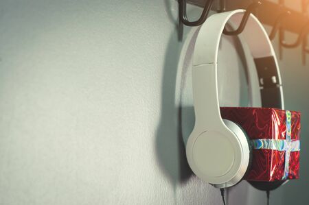 Red new year or christmas gift box with white headphone on blue or green  background. Copy space.