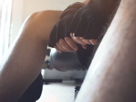 Concentration, Meditation before workout concept. Close up man hands wear gloves for barbell at the gym.の写真素材