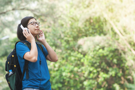 Happiness of Young Asian woman hiker with backpack listening music with headphone in nature.
Beautiful glasses girl closed her eyes and smiling with fresh air.の写真素材